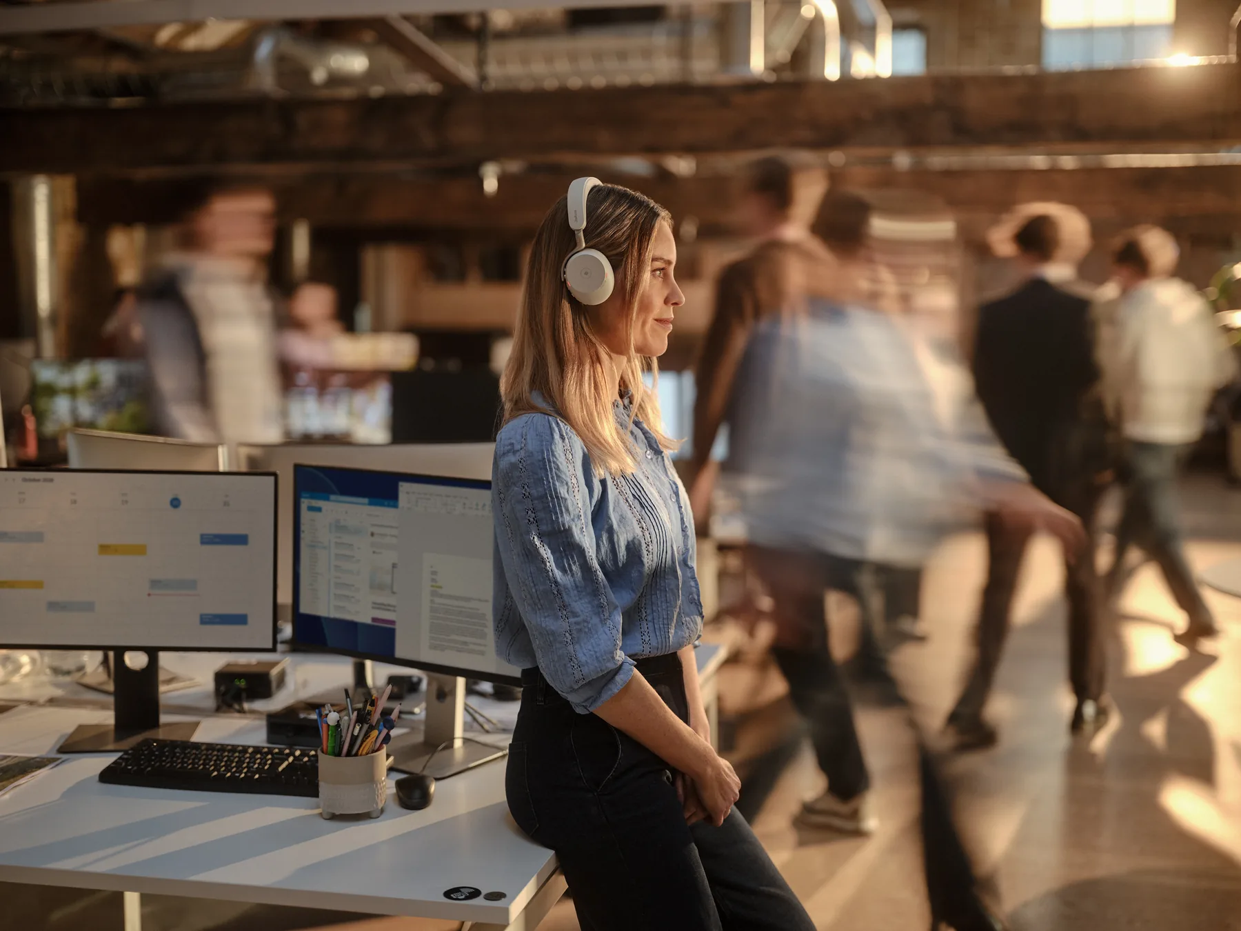Kobieta w słuchawkach Jabra Evolve3 75 pracująca przy dwóch monitorach